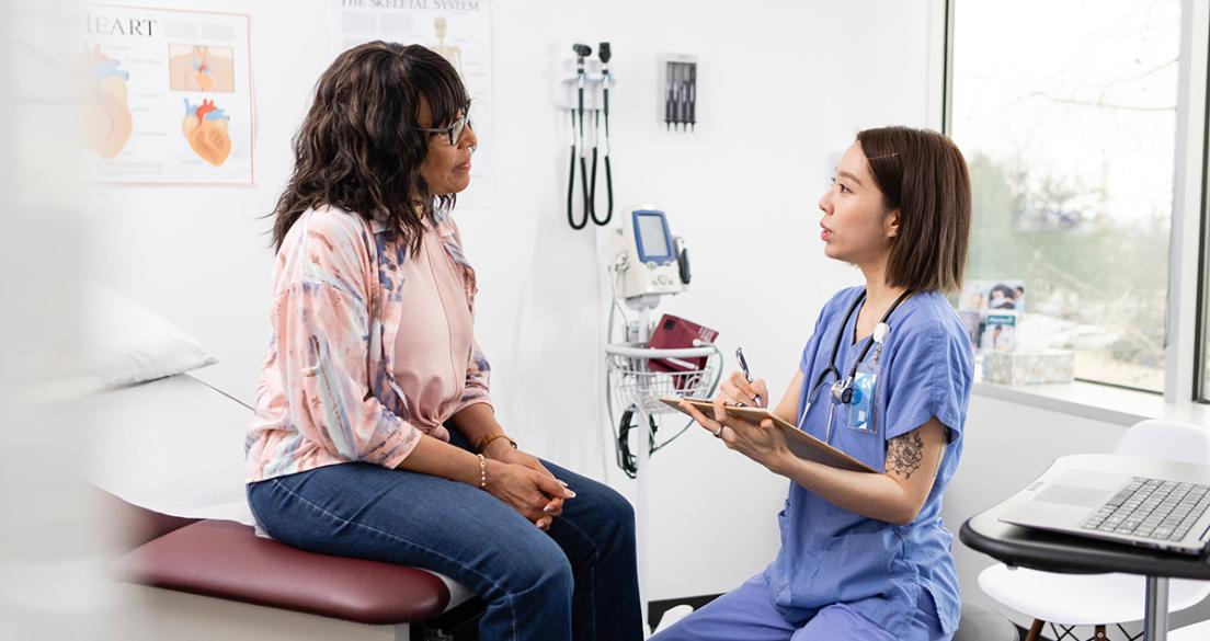 Female nurse makes notes while talking with the patient